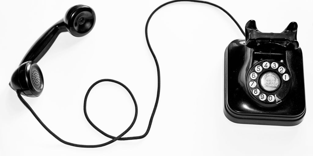 photo of black rotary phone against white background